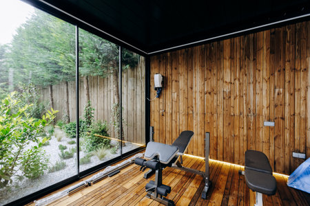 A gym with elegant wooden walls, a sturdy bench, and a large windowの写真素材