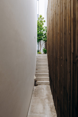 There is a narrow alleyway that features stairs along with a wooden fenceの写真素材