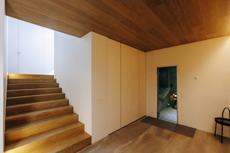 There is a hallway featuring wooden stairs and a charming wooden ceilingの写真素材