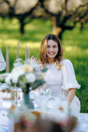 A woman in a beautiful white dress sits gracefully at a tableの写真素材