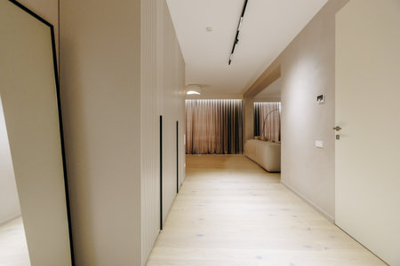 A long hallway with a wall mirror and a door to another roomの写真素材
