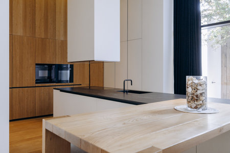 In a kitchen, there is a wooden table adorned with a vase filled with nutsの写真素材