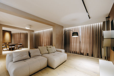 A cozy living room featuring a white couch paired with brown curtainsの写真素材