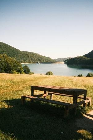 A picnic table in a beautiful field with a nearby lakeの写真素材
