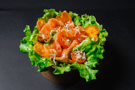 A bowl of salad with lettuce, tomatoes, carrots, and salmonの写真素材