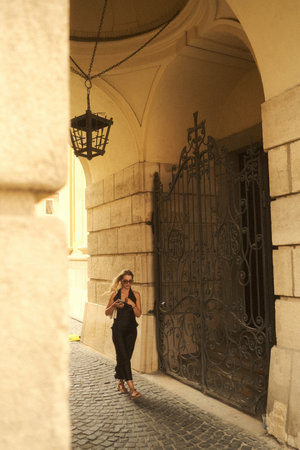 A woman dressed in a black dress is walking gracefully down a cobblestone streetの写真素材
