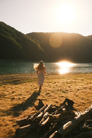 A woman in a white dress joyfully runs on a beach at sunsetの写真素材