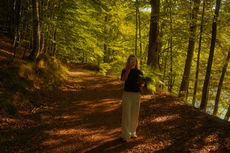 A woman is leisurely walking down a winding path in the woodsの写真素材