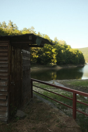 A charming shed by a serene lake, surrounded by treesの写真素材