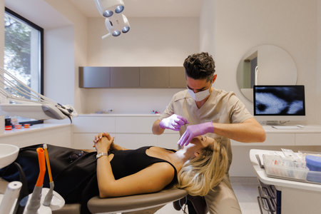A Dentist is Performing Treatment in a Modern and Advanced Dental Office Environmentの写真素材