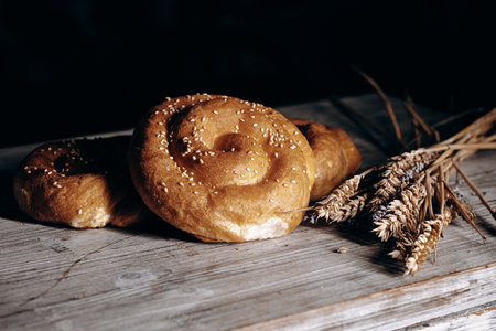 Freshly Baked Bread Rolls Accompanied by Wheat Stalks on a Rustic Wooden Table Setting