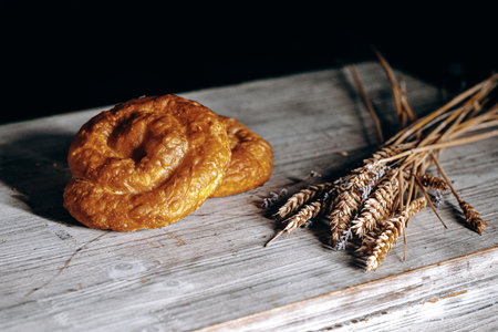 Deliciously Freshly Baked Pretzel with Wheat Stalks on a Rustic Wooden Table Environmentの写真素材