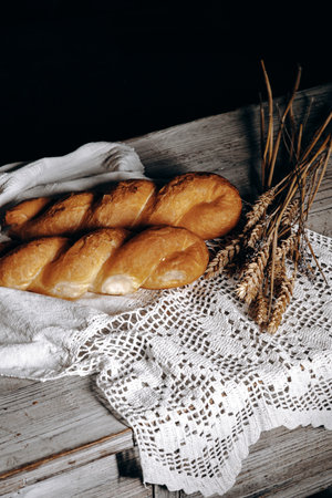 Deliciously Freshly Baked Bread Displayed on a Rustic Wooden Table with Beautiful Wheat Decorationの写真素材