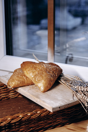 A beautifully crafted loaf of bread with wheat sheaves displayed by a sunny windowの写真素材