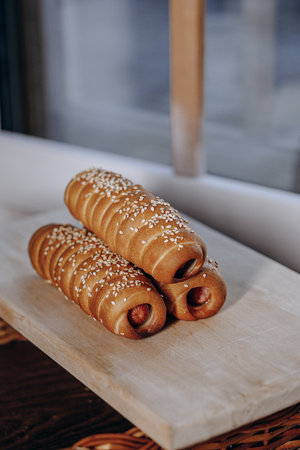 Savory and Delicious Hot Dog Rolls Topped with Crunchy Sesame Seeds on a Wooden Boardの写真素材