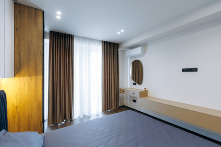 A Modern Bedroom Interior with Warm Lighting and Elegant Curtains for a cozy atmosphereの写真素材