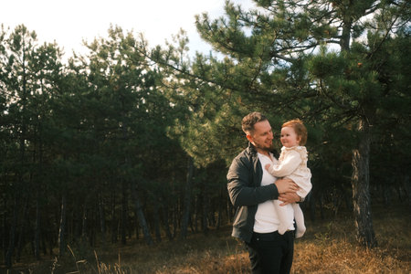 A Loving Father Embraces His Daughter in a Beautiful and Serene Nature Setting, Full of Warmthの写真素材