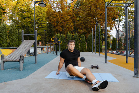 A man is actively exercising outdoors with a dumbbell in a beautiful autumn park settingの写真素材