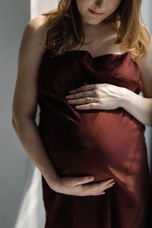 Pregnant caucasian woman maternity model in burgundy gownの写真素材