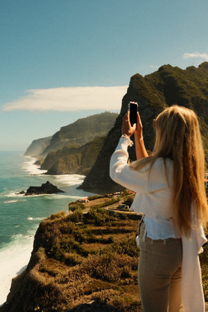 Casually dressed lady photographing wild sea cliffsの写真素材