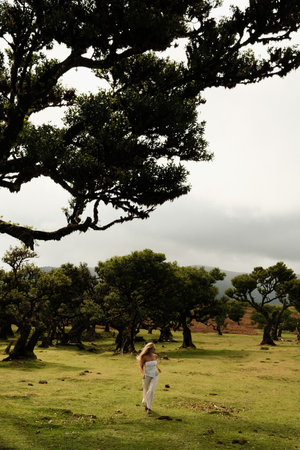 Running woman with flowing dress amidst scattered aged treesの写真素材