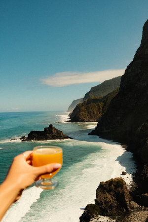 Photographer captures glass with sea and cliffs behind itの写真素材