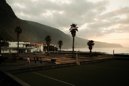 Sunset glow illuminates people walking by seaside courtの写真素材