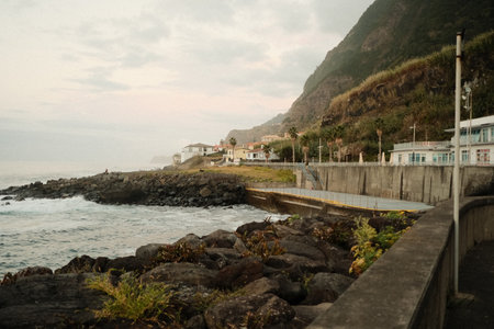 Serene coastal village beneath mountains during golden hourの写真素材