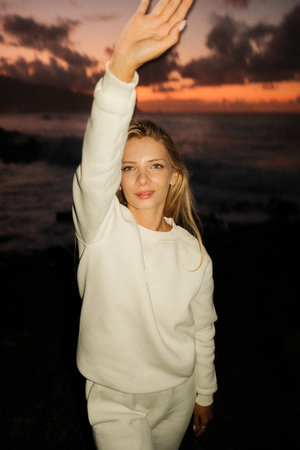 Travel blogger woman waving at sunset seaside golden hourの写真素材