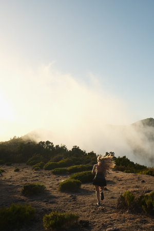 Wanderer making ascent amidst misty peaks during sunset glow