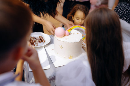 Young child gazes at colorful birthday cake with fascinationの写真素材