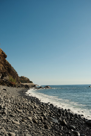 Sunlit shoreline with towering cliffs and tranquil ocean view