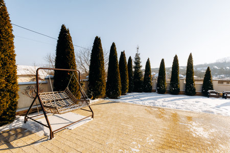 Sunny yard with snow patches, Serene outdoor space under clear skyの写真素材