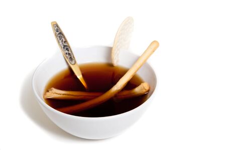 A white bowl of soup with cracker, photographed in the studio.