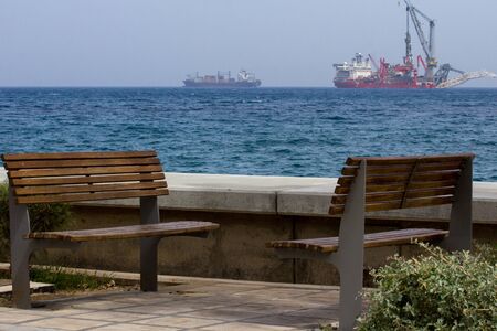 landscape with bench, sea and ships on the horizonの写真素材