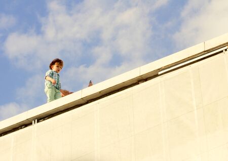 little boy walking through the parapet on the blue sky background. Moscow, 2017.08.13.のeditorial素材