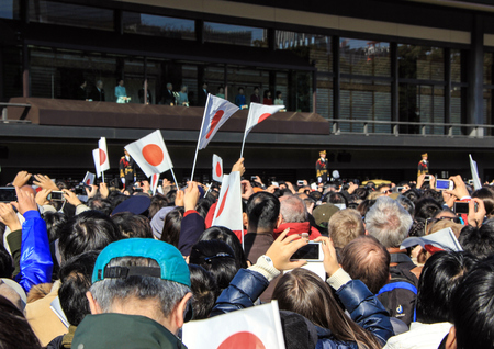 The crowd under the balcony in the square in front of the imperial palace on the first day of the New Year in Tokyo. People with national flags in the park.のeditorial素材