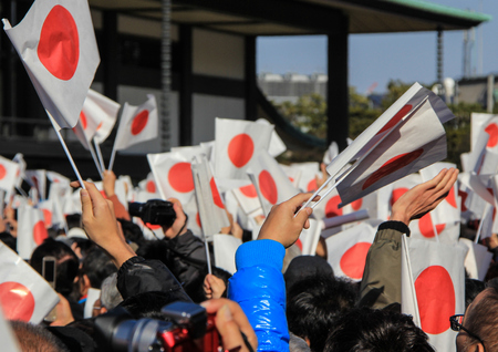 The crowd under the balcony in the square in front of the imperial palace on the first day of the New Year in Tokyo. People with national flags in the park.のeditorial素材