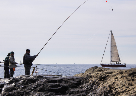 Fishermen and yaht on the rocks in the Pacific Ocean. Nature of Japan. Kamakura, Japan, 01/06/2013.のeditorial素材