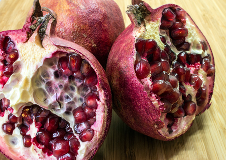A still life with cutted red pomegranate on the wooden background.の写真素材