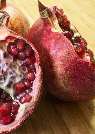 A still life with cutted red pomegranate on the wooden background.の写真素材