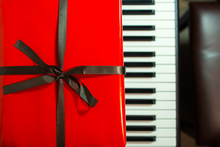 Big red present box on the piano. Christmas decoration of Interior. Happy birthday to you.の写真素材