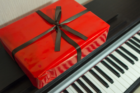 Big red present box on the piano. Christmas decoration of Interior. Happy birthday to you.の写真素材