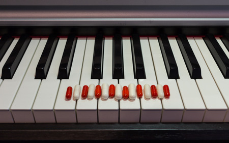 Pills on the piano keyboard. Concept of music and health.の写真素材