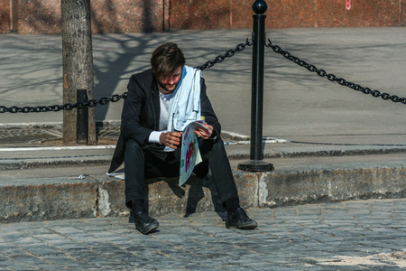 2010.04.11, Moscow, Russia. A man reading news paper sitting on the Red square. Tourists walking around Moscow.のeditorial素材