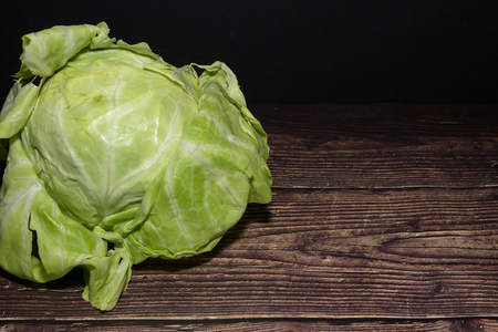 Fresh cabbage on wooden background in the dark. vegetarian food close up.の写真素材