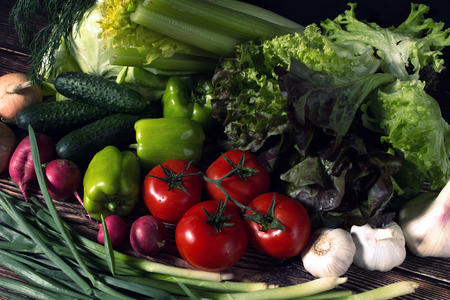set of fresh vegetables in the dark. vegetarian food on wooden background. vegetable harvest from the garden.の写真素材