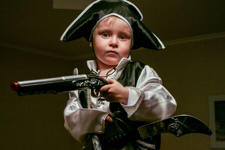 2010.11.28, Maloyaroslavets, Russia. A little boy wearing a pirate costume holds a knife and a gun. Carnival costume of cute kid, blurred and grain effect.の写真素材