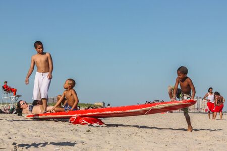 2012.06.17, New York, United States of America. Group of little boys playing on surf board at the...