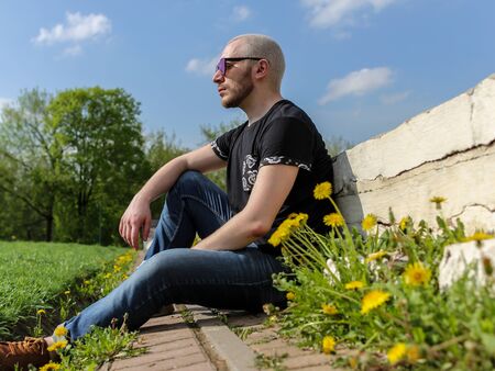 05/08/2019, Moscow, Russia. A young bearded blonde man sitting by ruins at spring park. A guy...